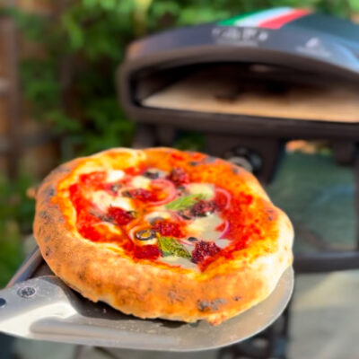 A freshly baked pizza straight out of the pizza oven showing the delicious melted cheese and fresh ingredients